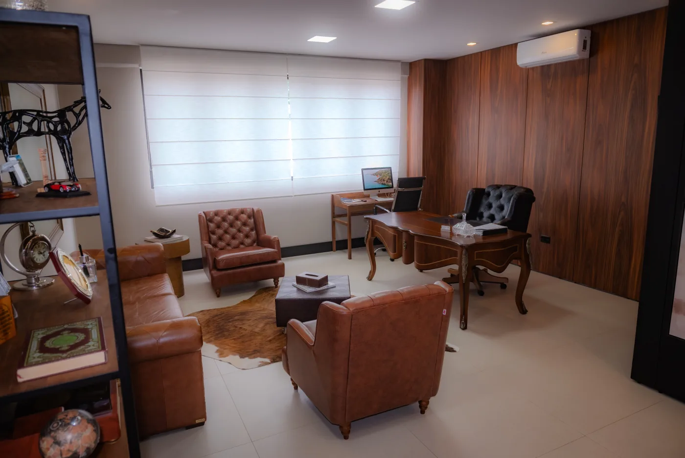 Sala privativa do escritório com mobiliário em madeira e poltronas de couro